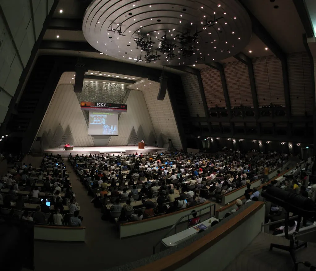 A large conference auditorium with delegates seated before a stage.