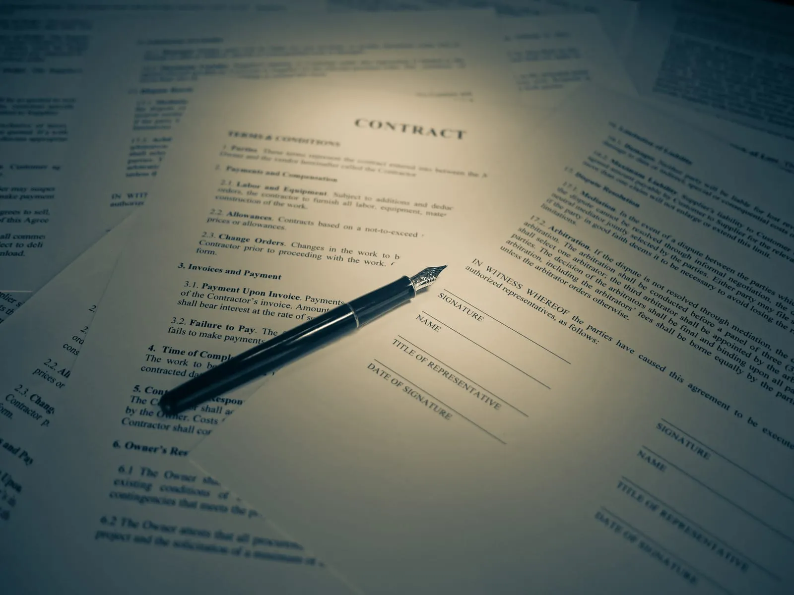 A printed contract showing terms and conditions, with a fountain pen resting on it.