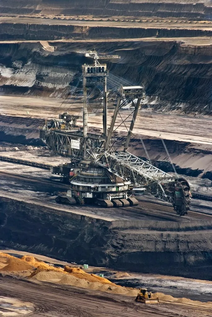 An open-pit mine with cut benches and a dozer working a stockpile.