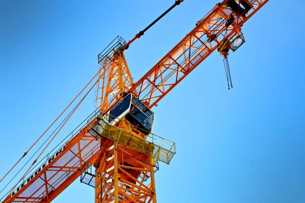 A tower crane seen from below against a clear sky.
