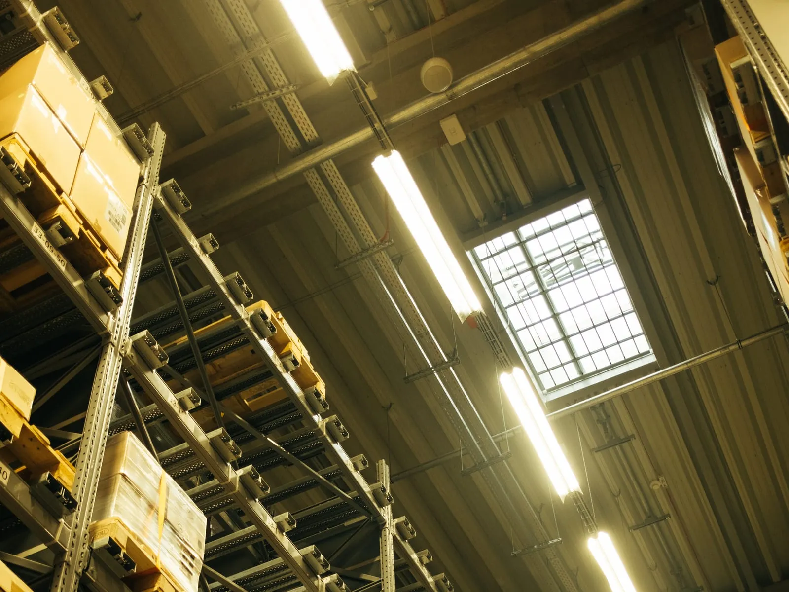 Tall pallet racking stacked with boxed goods along a lit warehouse aisle.